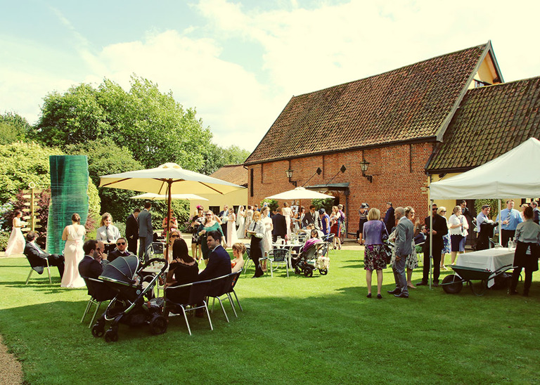 A summer wedding reception at Haughley Park Barn Wedding Venue with guests mingling on the lawns photographed by Suffolk Wedding Photographers Hayley Denston Photography