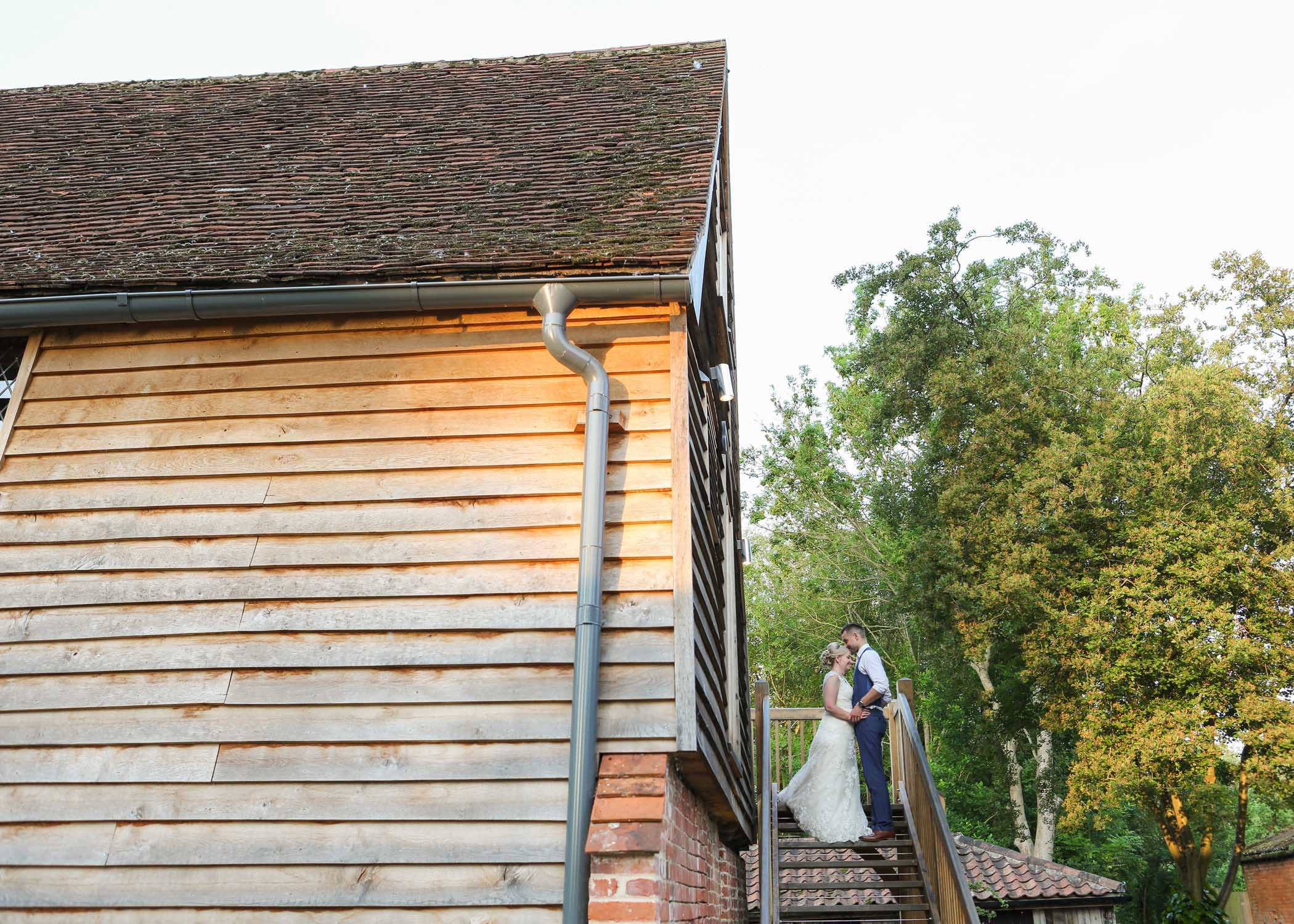 A bride and groom kissing up the steps of the barn at Tudor Barn Belstead Wedding Venue on their wedding day photographed by Suffolk Wedding Photographers Hayley Denston Photography