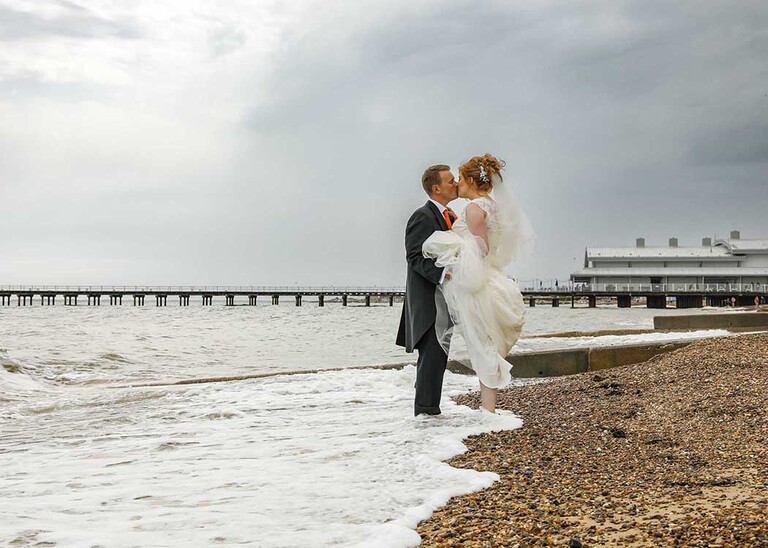 A bride and groom paddling in the sea on a beach wedding in Suffolk photographed by Suffolk Wedding Photographers Hayley Denston Photography