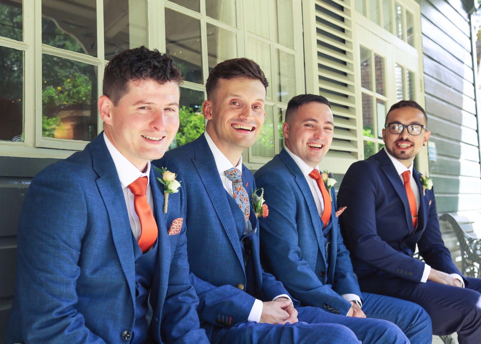 A groom and his groomsmen sat smiling before his wedding ceremony at The Pavillion at Ravenwood Hall Wedding Venue in Suffolk photographed by Suffolk Wedding Photographers Hayley Denston Photography
