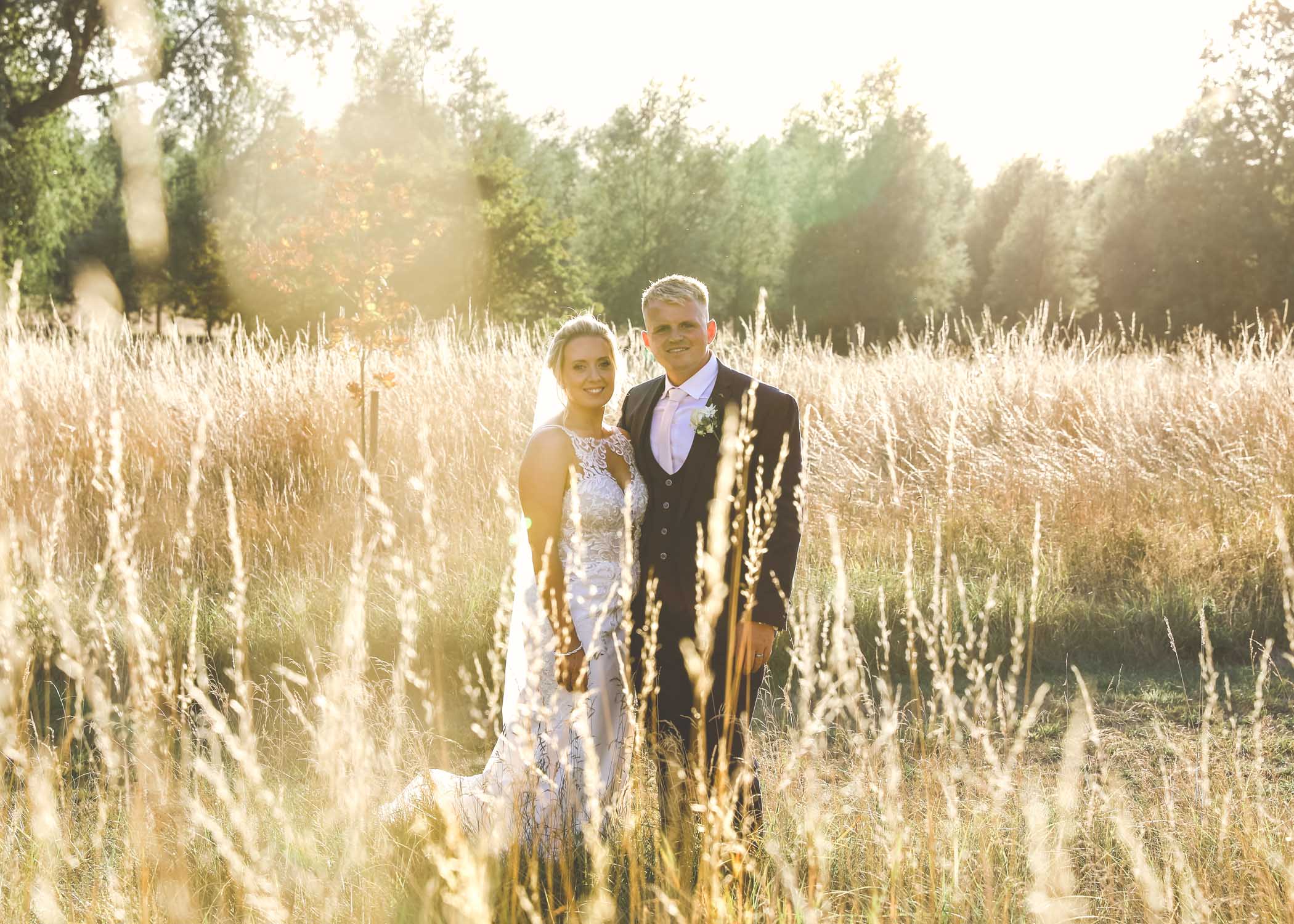 A bride and groom in the meadows at sunset at Easton Grange Wedding Venue on their wedding day captured by Suffolk Wedding Photographers Hayley Denston Photography