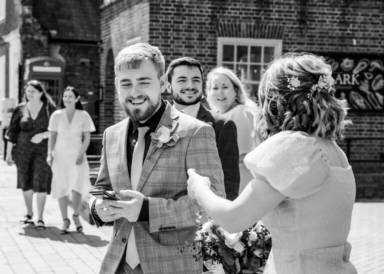 Guests laughing before the ceremony on a wedding day at Bury St Edmunds Registry Office in Suffolk captured by Suffolk Wedding Photographers Hayley Denston Photography