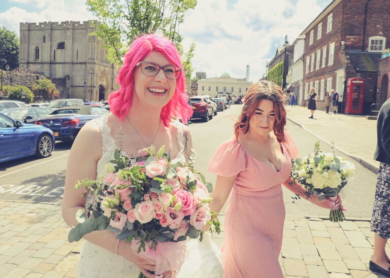 A bride and her bridesmaid walking to her wedding ceremony at Bury St Edmunds Registry Office in Suffolk captured by Suffolk Wedding Photographers Hayley Denston Photography