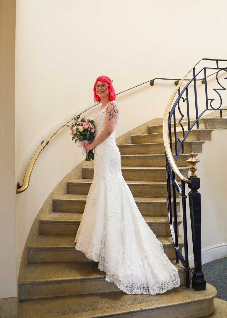 A bride on the stairs on her wedding day before the ceremony at Bury St Edmunds Registry Office in Suffolk captured by Suffolk Wedding Photographers Hayley Denston Photography
