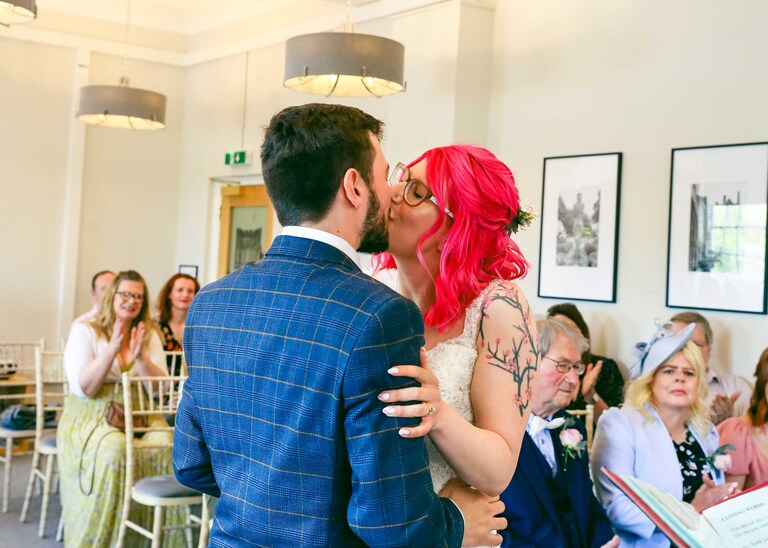 A bride and groom kissing during their wedding ceremony at Bury St Edmunds Registry Office on their wedding day in Suffolk captured by Suffolk Wedding Photographers Hayley Denston Photography