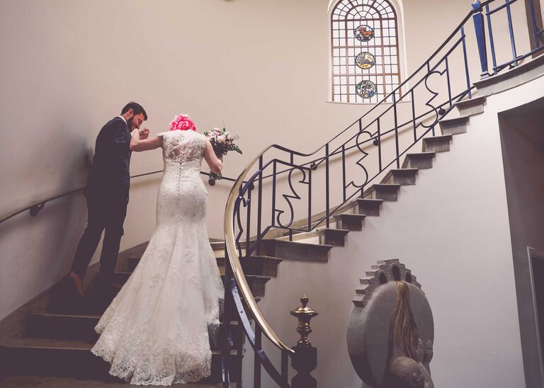 A bride and groom walking up the stairs in Bury St Edmunds Registry Office on their wedding day in Suffolk captured by Suffolk Wedding Photographers Hayley Denston Photography
