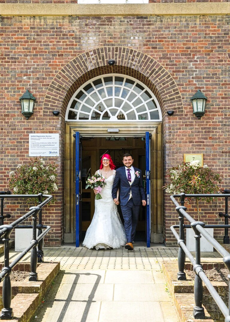 A bride and groom walking out of Bury St Edmunds Registry Office on their wedding day in Suffolk captured by Suffolk Wedding Photographers Hayley Denston Photography