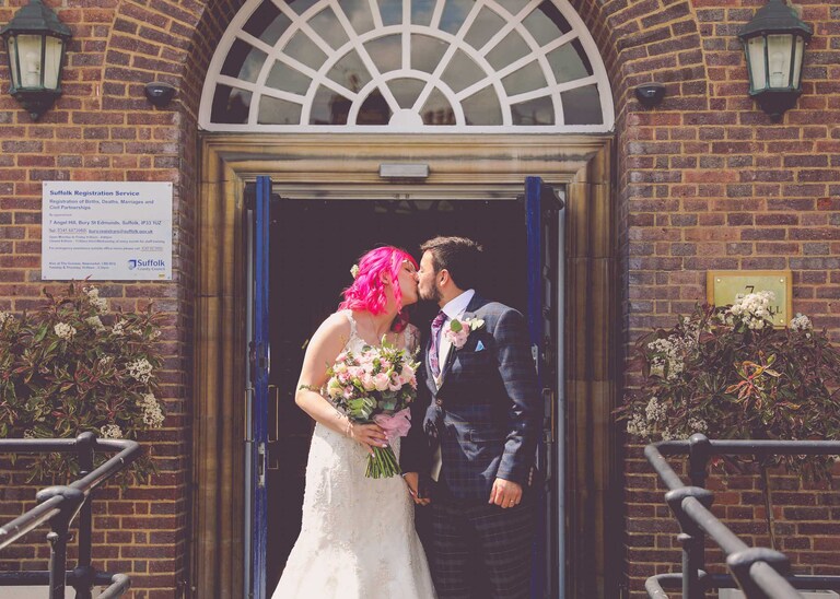 A bride and groom kissing outside of Bury St Edmunds Registry Office on their wedding day in Suffolk captured by Suffolk Wedding Photographers Hayley Denston Photography