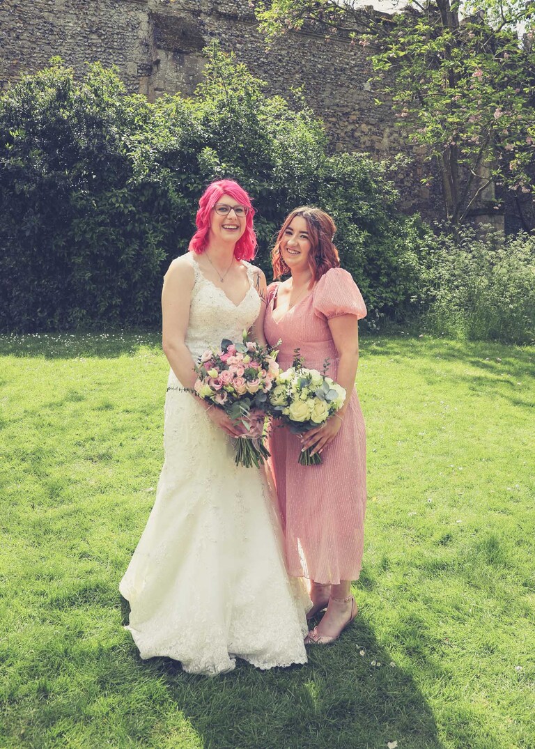 A bride and her bridesmaid in the Abbey Gardens in Bury St Edmunds on a wedding day in Suffolk captured by Suffolk Wedding Photographers Hayley Denston Photography