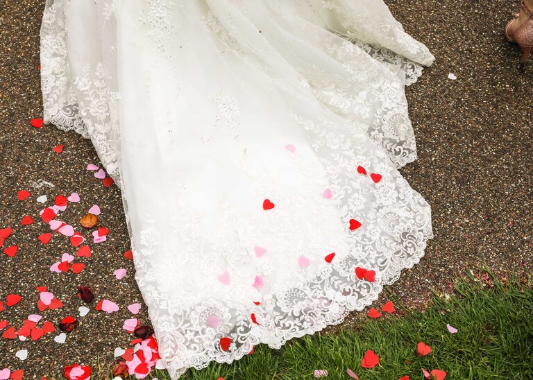 A brides dress train with loveheart confetti on it in the Abbey Gardens in Bury St Edmunds on a wedding day in Suffolk captured by Suffolk Wedding Photographers Hayley Denston Photography