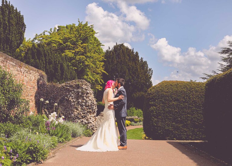 A bride and groom kissing in the gardens in the Abbey Gardens in Bury St Edmunds on a wedding day in Suffolk captured by Suffolk Wedding Photographers Hayley Denston Photography