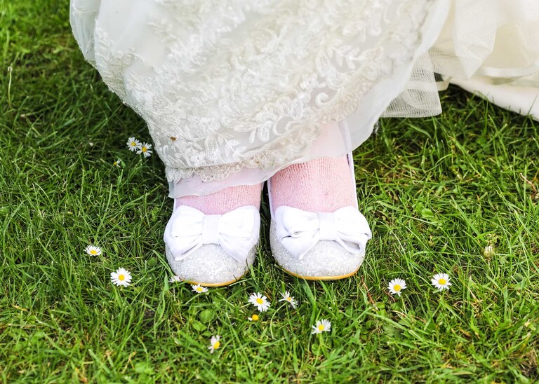 A brides shoes with pink socks on in the Abbey Gardens in Bury St Edmunds on a wedding day in Suffolk captured by Suffolk Wedding Photographers Hayley Denston Photography