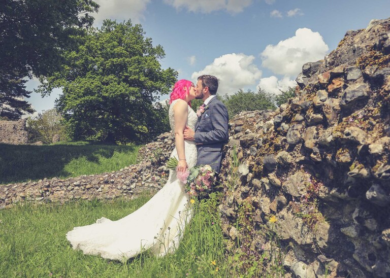 A bride and groom kissing with the ruins of the Abbey in the Abbey Gardens in Bury St Edmunds on a wedding day in Suffolk captured by Suffolk Wedding Photographers Hayley Denston Photography
