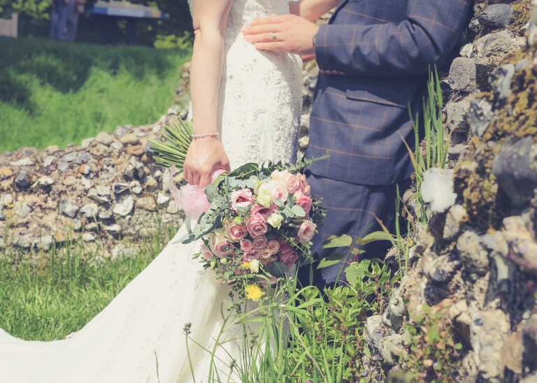 A brides bouquet and the ruins of the Abbeyin the Abbey Gardens in Bury St Edmunds on a wedding day in Suffolk captured by Suffolk Wedding Photographers Hayley Denston Photography