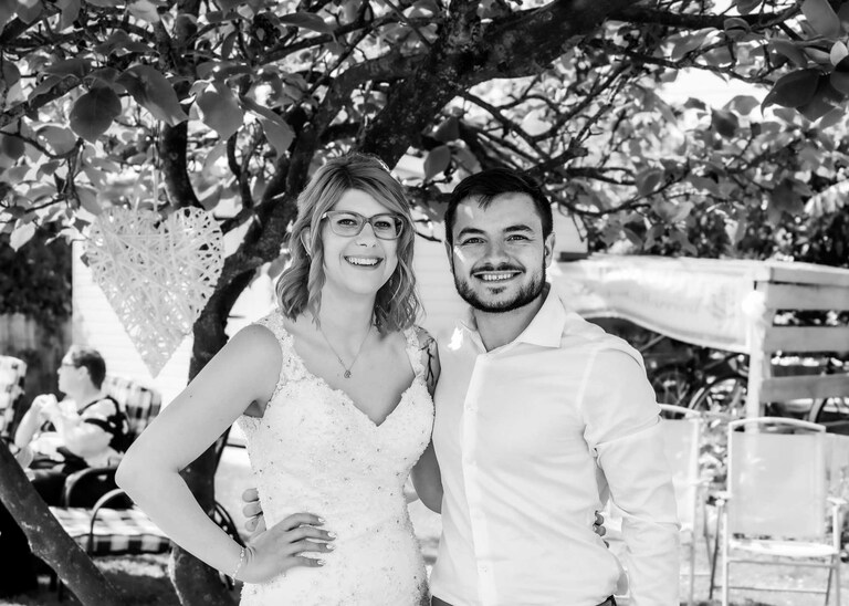 A bride and groom smiling under a magnolia tree on a wedding day in Suffolk captured by Suffolk Wedding Photographers Hayley Denston Photography