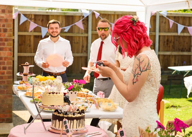 A bride looking at a tiny motorbike on her wedding cake on a wedding day in Suffolk captured by Suffolk Wedding Photographers Hayley Denston Photography