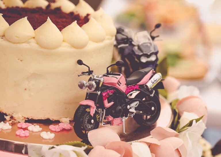 Two little painted motorbikes on a wedding cake on a wedding day in Suffolk captured by Suffolk Wedding Photographers Hayley Denston Photography