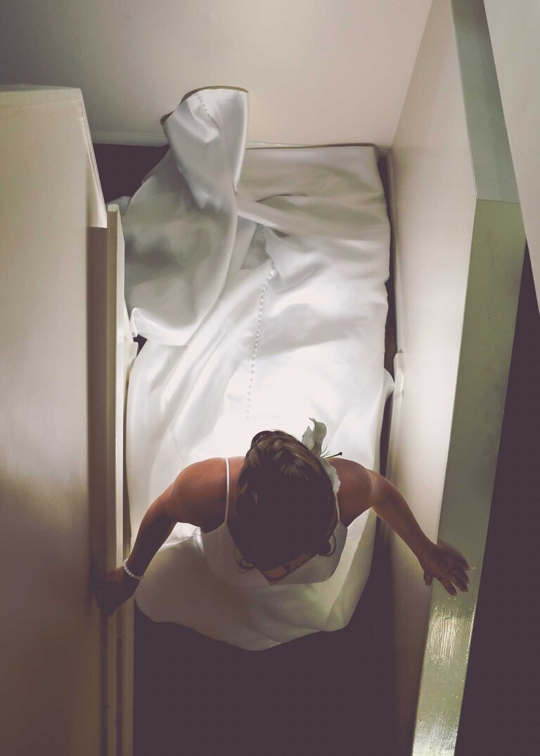 A bride walking down the stairs from above on her weddign day at Hungarian Hall on a Wedding Day photographed by Suffolk Wedding Photographers Hayley Denston Photography
