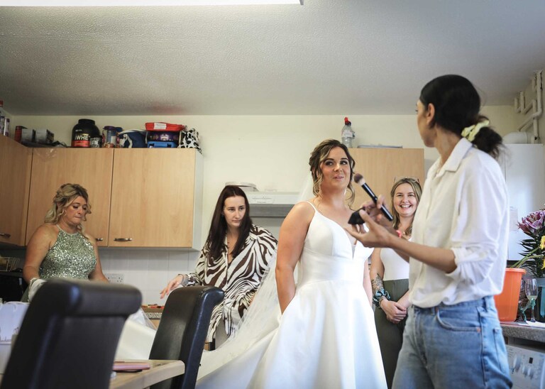 A bride having her make up done in the kitchen on her wedding day at Hungarian Hall on a Wedding Day photographed by Suffolk Wedding Photographers Hayley Denston Photography