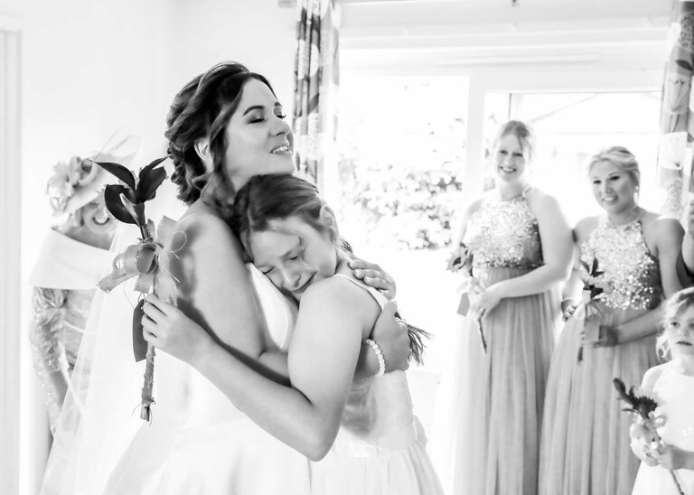 A bride cuddling her tearful daughter before her wedding ceremony at Hungarian Hall on a Wedding Day photographed by Suffolk Wedding Photographers Hayley Denston Photography