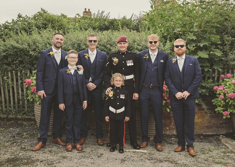A groom and his groomsmen in a formal photo before an outdoor wedding ceremony at Hungarian Hall on a Wedding Day photographed by Suffolk Wedding Photographers Hayley Denston Photography