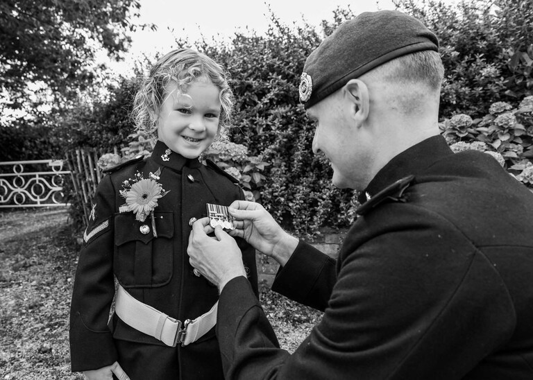 A groom putting on his sons medals before th ewedding ceremony at Hungarian Hall on a Wedding Day photographed by Suffolk Wedding Photographers Hayley Denston Photography
