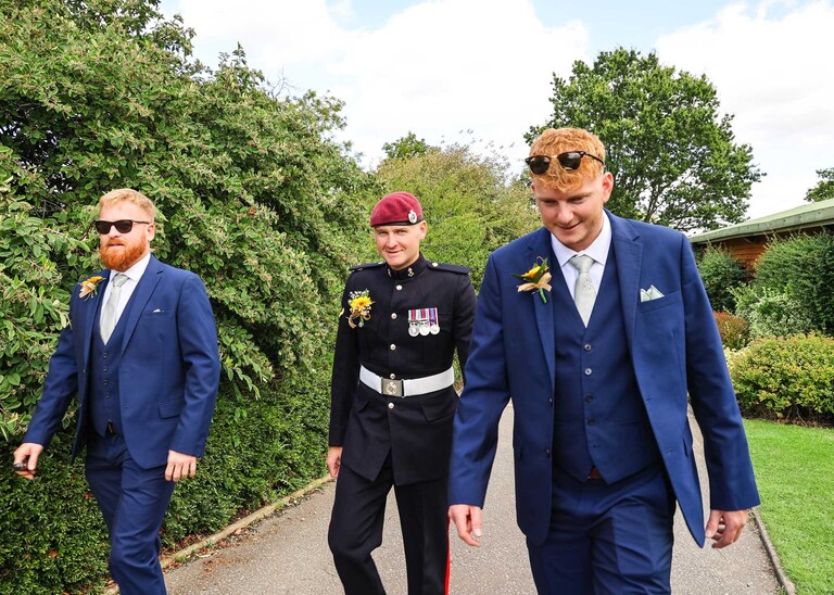 The groom and his grooms party walking towards the outdoor wedding ceremony at Hungarian Hall on a Wedding Day photographed by Suffolk Wedding Photographers Hayley Denston Photography