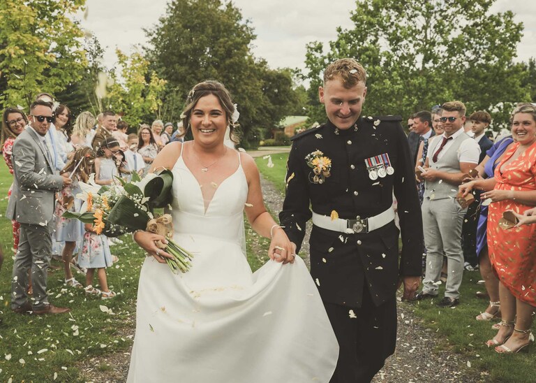 A bride and groom walking through a confetti aisle at Hungarian Hall on a Wedding Day photographed by Suffolk Wedding Photographers Hayley Denston Photography