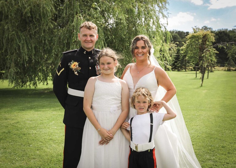 A bride and groom formal photo with their children at Hungarian Hall on a Wedding Day photographed by Suffolk Wedding Photographers Hayley Denston Photography