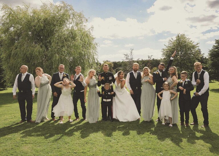 A bridal party striking a pose during their formal group shots at Hungarian Hall on a Wedding Day photographed by Suffolk Wedding Photographers Hayley Denston Photography