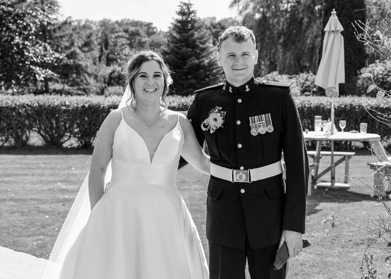 A bride and groom with their arms behind each other waiting to be announced in to their wedding breakfast at Hungarian Hall on a Wedding Day photographed by Suffolk Wedding Photographers Hayley Denston Photography