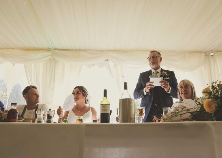 A father of the bride giving his speech with the top table at Hungarian Hall on a Wedding Day photographed by Suffolk Wedding Photographers Hayley Denston Photography