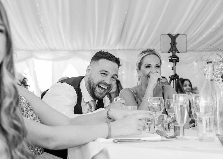 A guest laughing during speeches at Hungarian Hall on a Wedding Day photographed by Suffolk Wedding Photographers Hayley Denston Photography