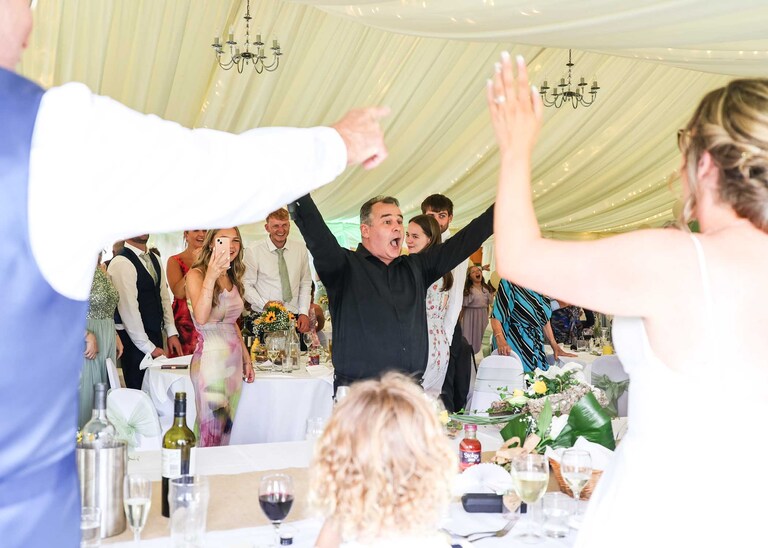 A singing waiter performing in a marquee at Hungarian Hall on a Wedding Day photographed by Suffolk Wedding Photographers Hayley Denston Photography