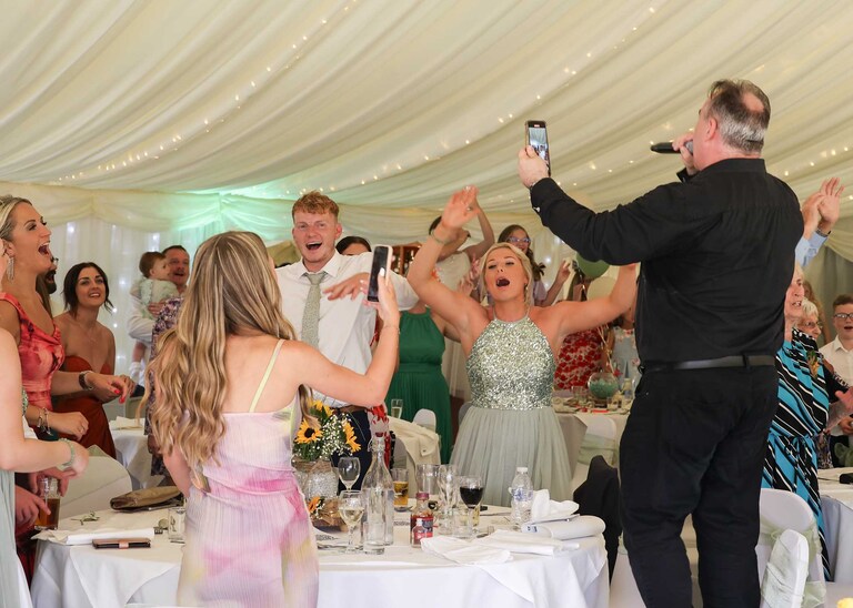 A singing waiter and guests joining in at Hungarian Hall on a Wedding Day photographed by Suffolk Wedding Photographers Hayley Denston Photography