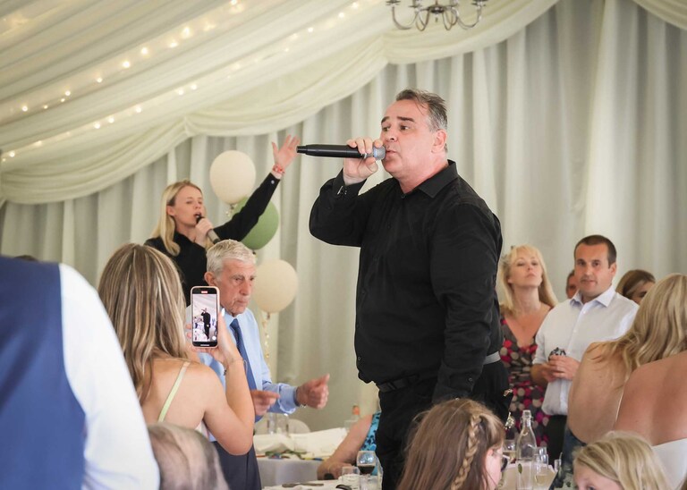 A singing waiters performance in a marquee at Hungarian Hall on a Wedding Day photographed by Suffolk Wedding Photographers Hayley Denston Photography