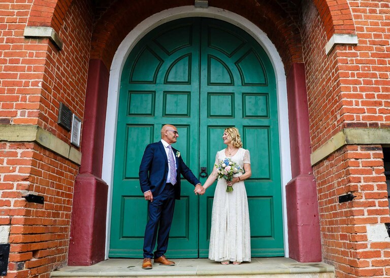 A bride and groom looking at each other in front of the big green doors at Woodbridge Shire Hall on their wedding day photographed by Suffolk Wedding Photographers Hayley Denston Photography
