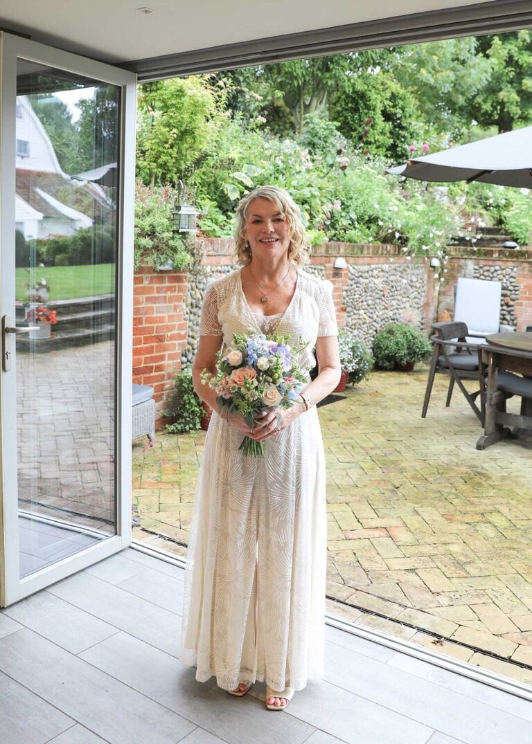 A bride in a doorway in her vintage wedding dress on a rainy wedding day at Letheringham Water Mill by Suffolk Wedding Photographers Hayley Denston Photography