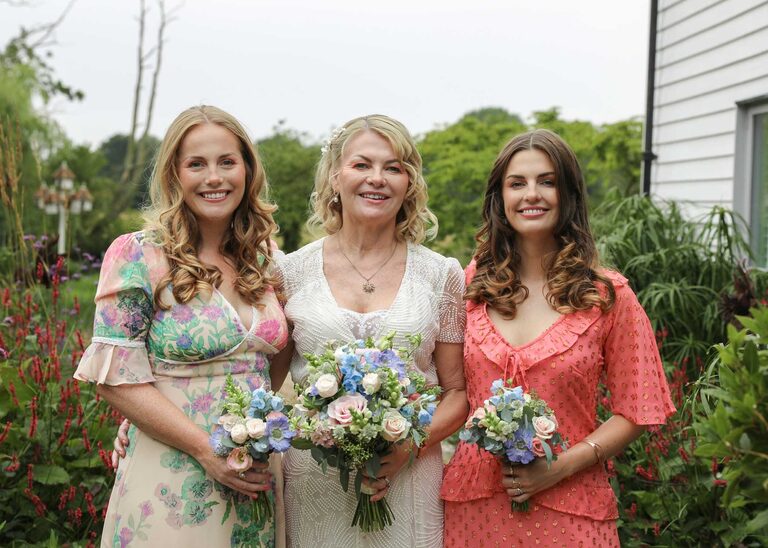 A bride and her daughters in the rain at Letheringham Water Mill on their wedding day by Suffolk Wedding Photographers Hayley Denston Photography
