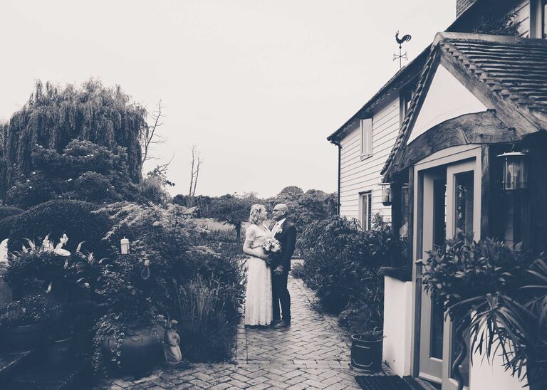 A bride and groom looking at each other in the rain at Letheringham Water Mill on their wedding day by Suffolk Wedding Photographers Hayley Denston Photography