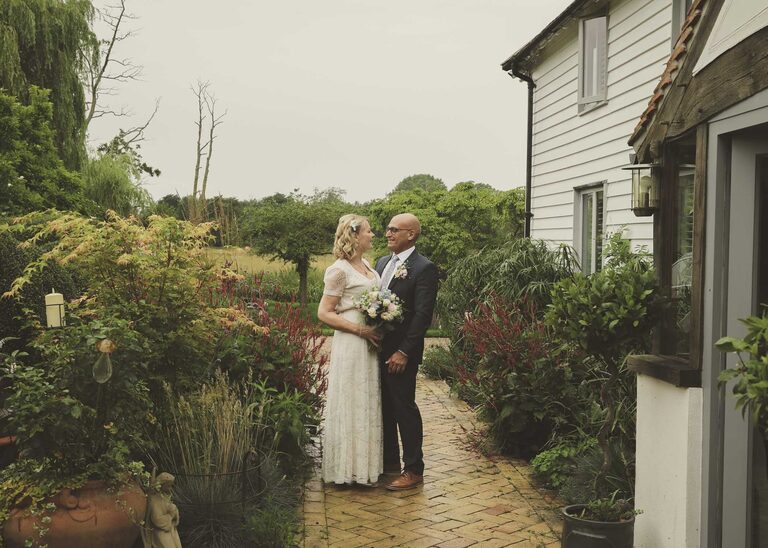 A bride and groom looking at each other in the rain at Letheringham Water Mill on their wedding day by Suffolk Wedding Photographers Hayley Denston Photography