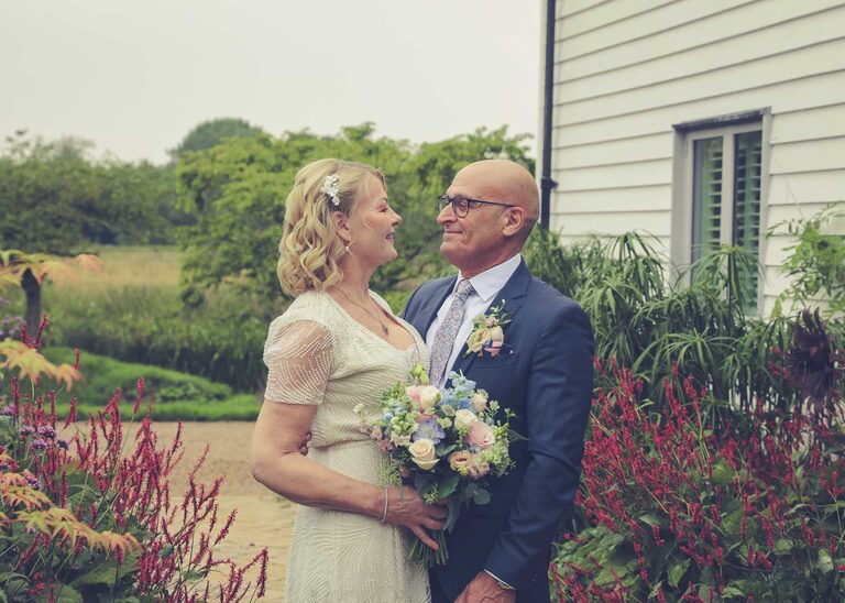 A bride and groom looking at each other in the rain at Letheringham Water Mill on their wedding day by Suffolk Wedding Photographers Hayley Denston Photography