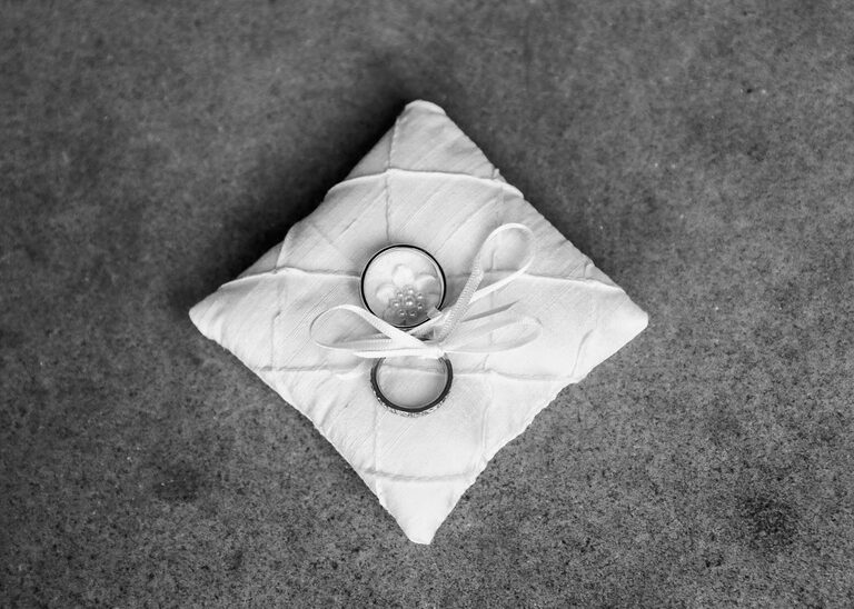 A little ring cushion with wedding rings on it at Woodbridge Shire Hall on a rainy day photographed by Suffolk Wedding Photographers Hayley Denston Photography