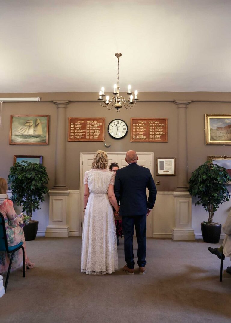 A bride and groom holding hands at a wedding ceremony at Woodbridge Shire Hall photographed by Suffolk Wedding Photographers Hayley Denston Photography