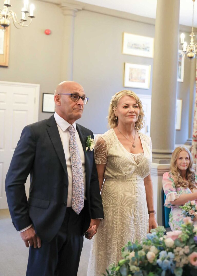 A bride and groom holding hands at a wedding ceremony at Woodbridge Shire Hall photographed by Suffolk Wedding Photographers Hayley Denston Photography