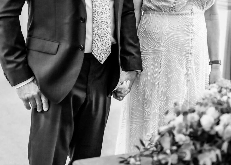 A bride and groom holding hands at a wedding ceremony at Woodbridge Shire Hall photographed by Suffolk Wedding Photographers Hayley Denston Photography