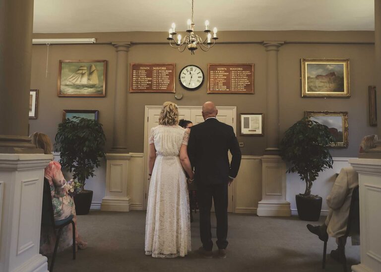 A bride and groom holding hands at a wedding ceremony at Woodbridge Shire Hall photographed by Suffolk Wedding Photographers Hayley Denston Photography