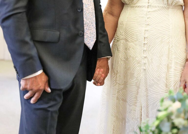A bride and groom holding hands at a wedding ceremony at Woodbridge Shire Hall photographed by Suffolk Wedding Photographers Hayley Denston Photography