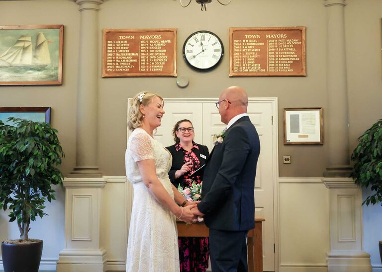 A bride and groom holding hands at a wedding ceremony at Woodbridge Shire Hall photographed by Suffolk Wedding Photographers Hayley Denston Photography