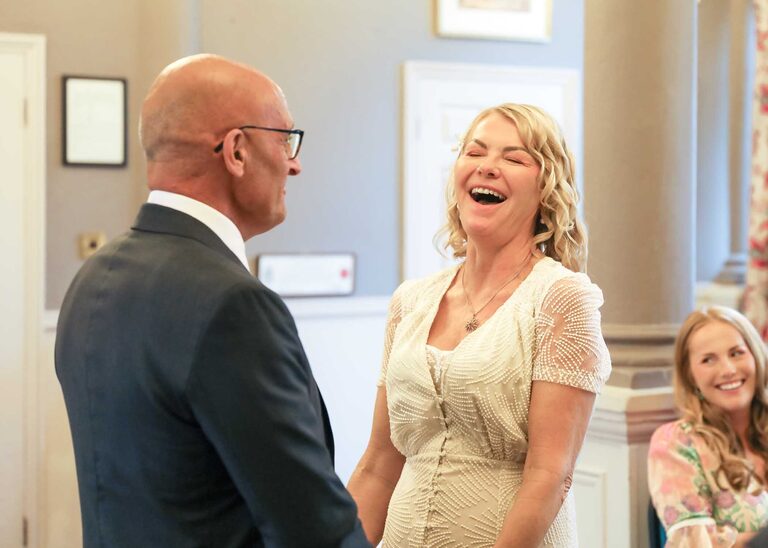 A bride laughing at a wedding ceremony at Woodbridge Shire Hall photographed by Suffolk Wedding Photographers Hayley Denston Photography